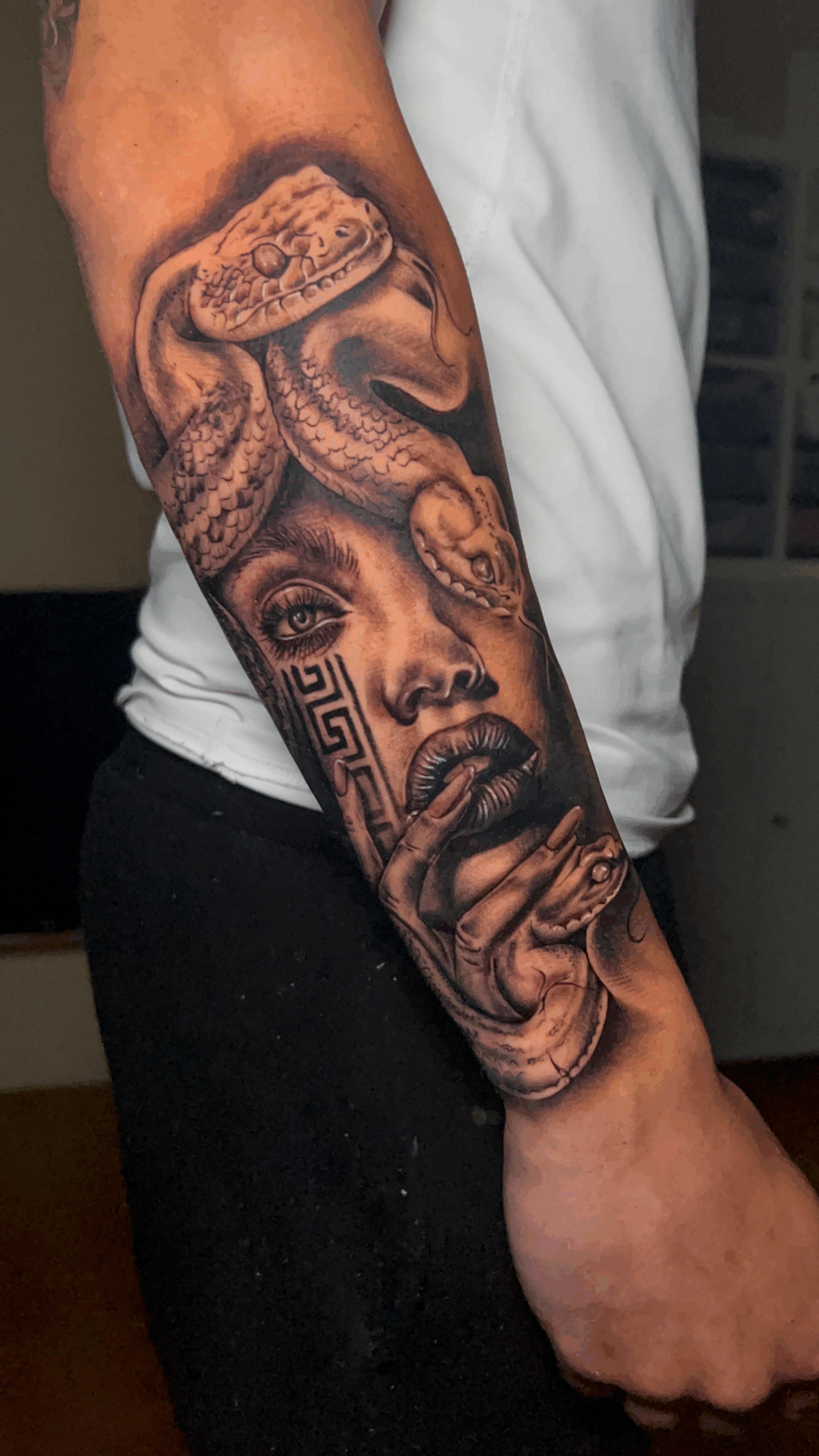 Tatuaje en brazo de rostro femenino con serpiente y elementos decorativos aztecas en estilo realista