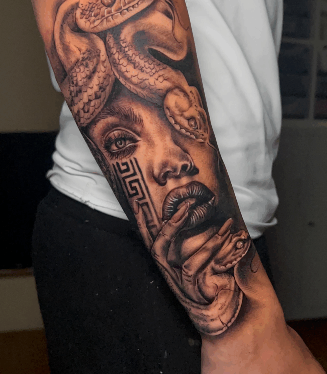 Tatuaje en brazo de rostro femenino con serpiente y elementos decorativos aztecas en estilo realista