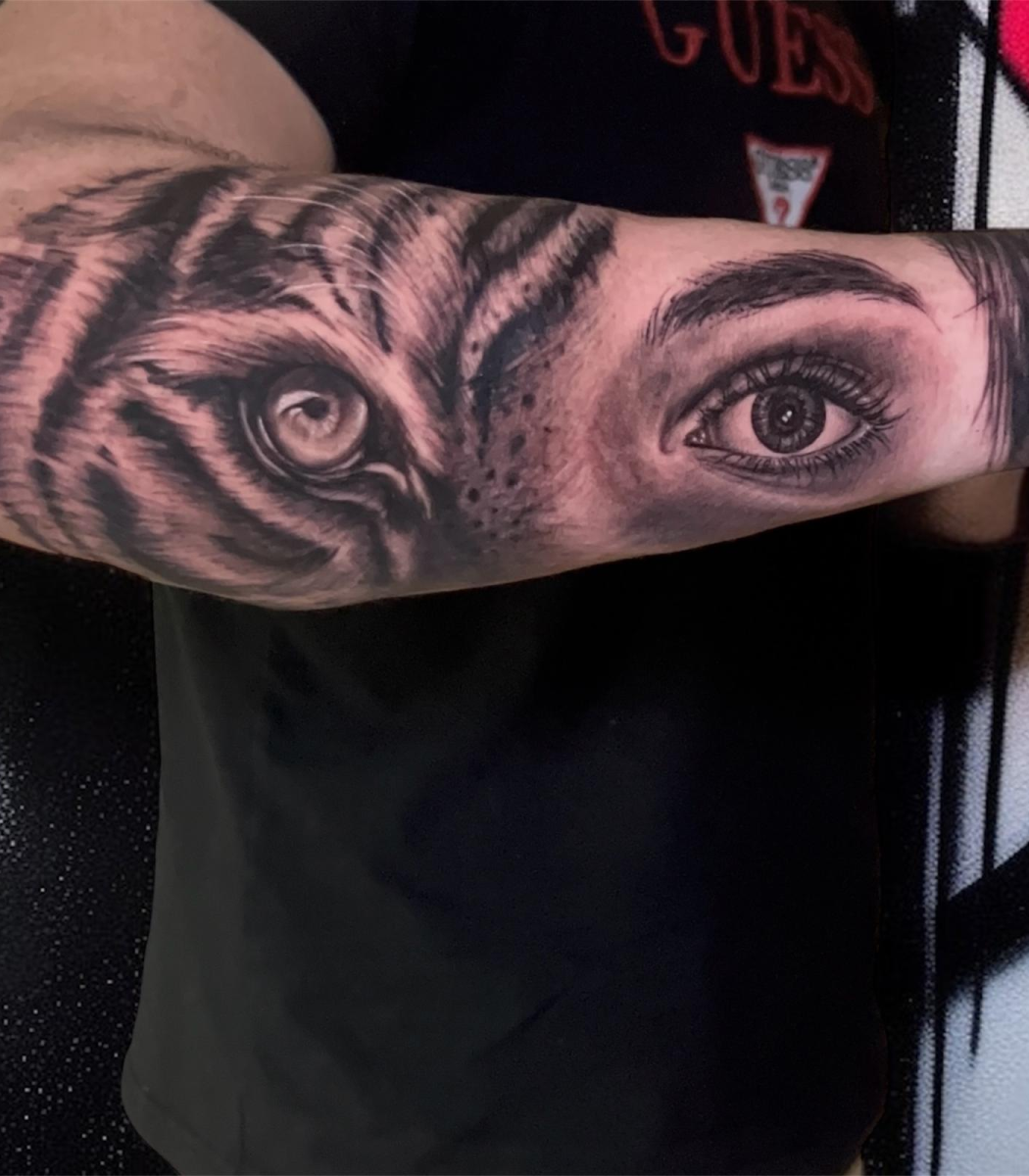 Tatuaje realista en bíceps de ojo de tigre y ojo humano en estilo hiperrealista