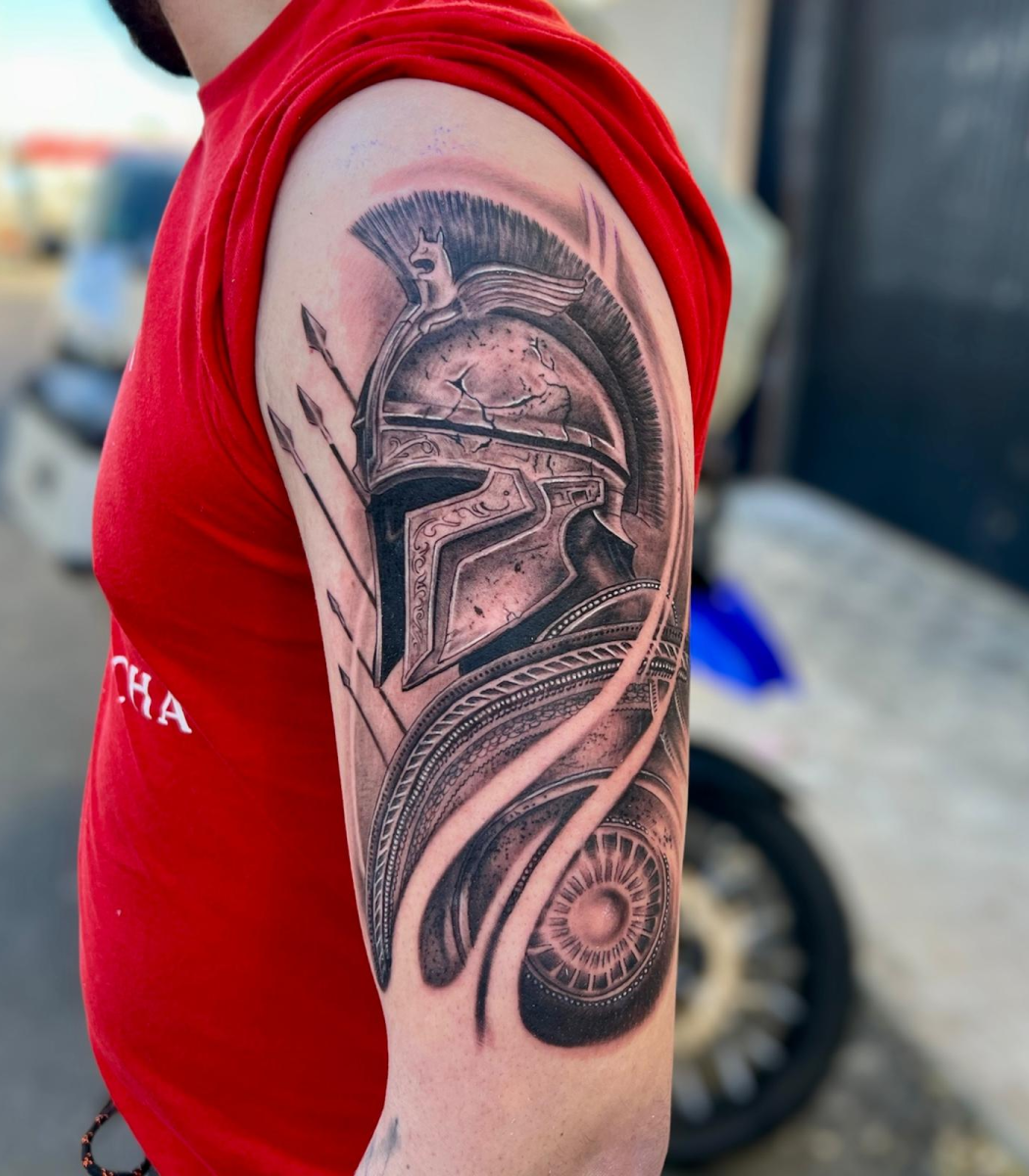 Tatuaje en brazo de casco de guerrero espartano con plumas estilo realista